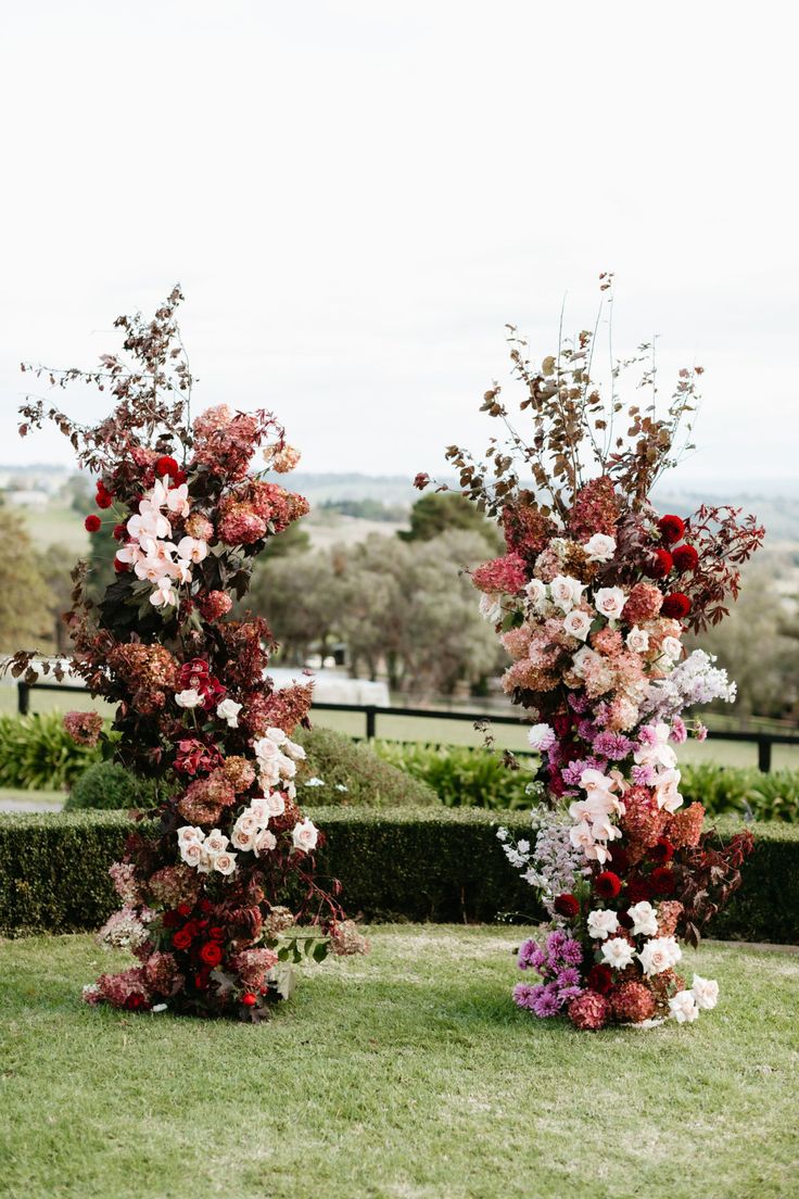 two tall vases with flowers are on the grass