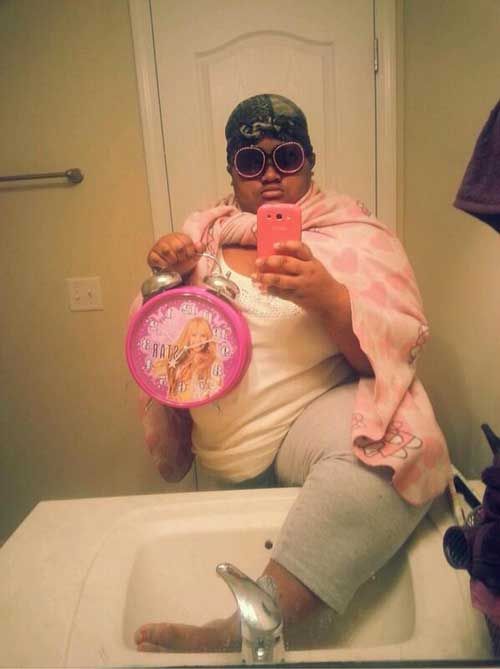 a woman taking a selfie in the bathroom mirror with her pink hair and sunglasses