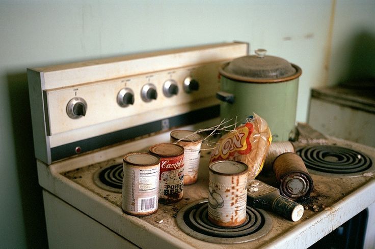 an old stove with some tins on it and other items sitting on the burners