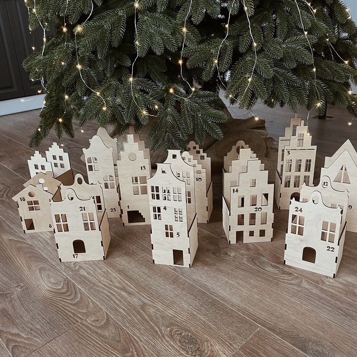 small wooden houses sitting next to a christmas tree