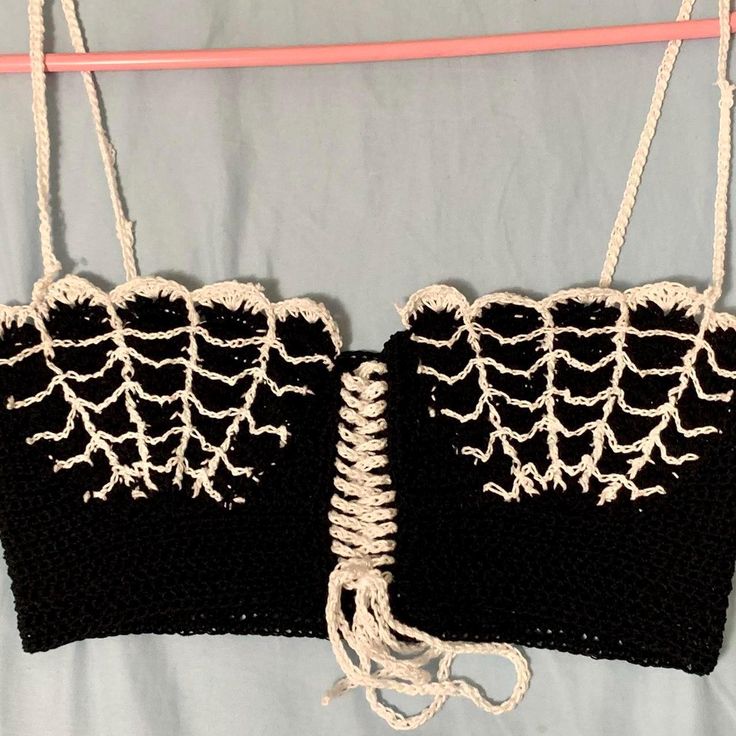 two crocheted black and white purses hanging from a clothes line on a bed