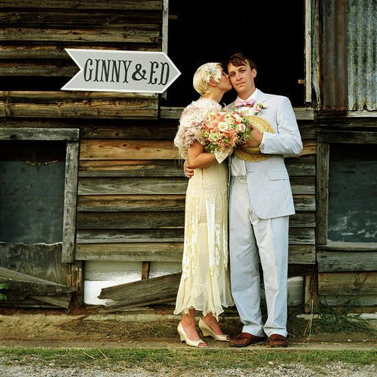 a man and woman are kissing in front of a wooden building with a sign that says,