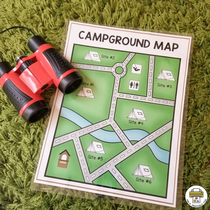 a red toy car sitting on top of a green field next to a paper map