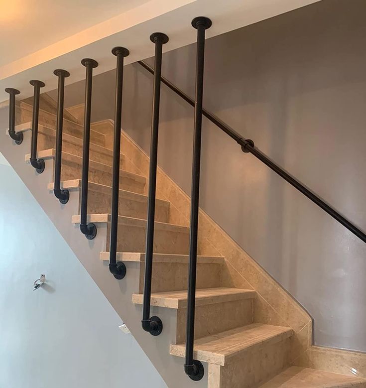 a set of stairs leading up to the second floor in a home with white walls and black metal handrails