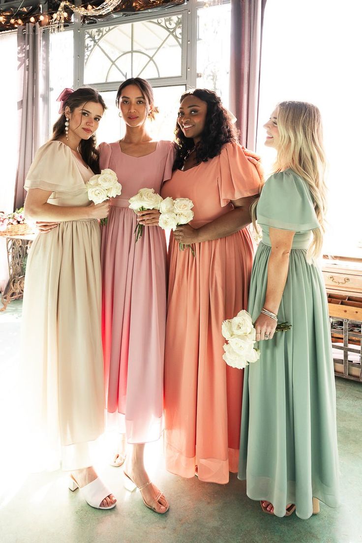 four bridesmaids pose for a photo in front of a window