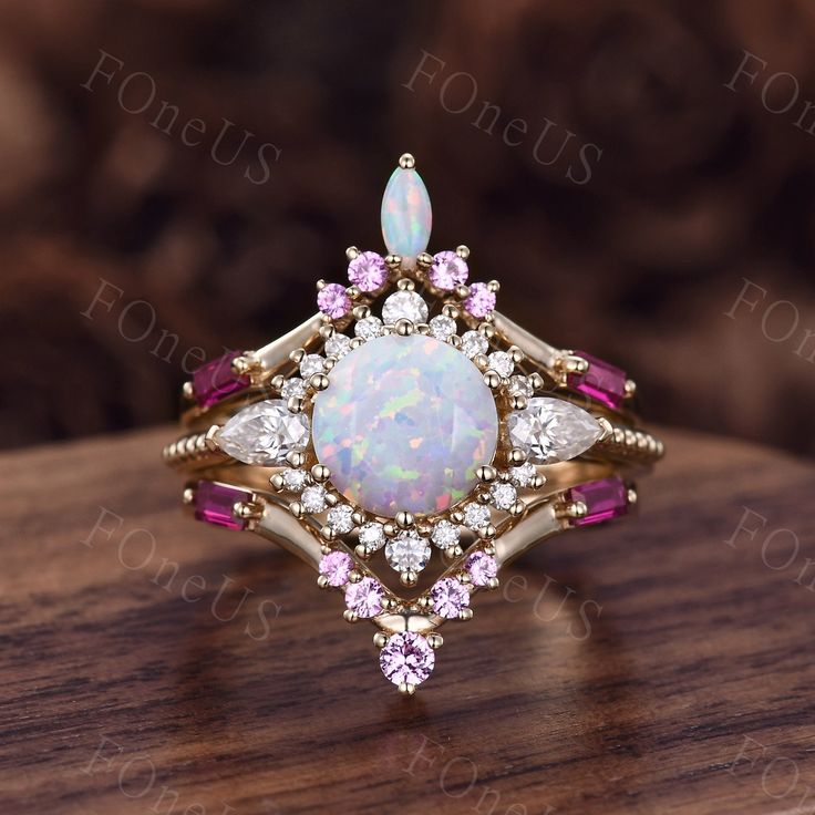 an opal and pink tourmaline ring with diamond accents on a wooden surface