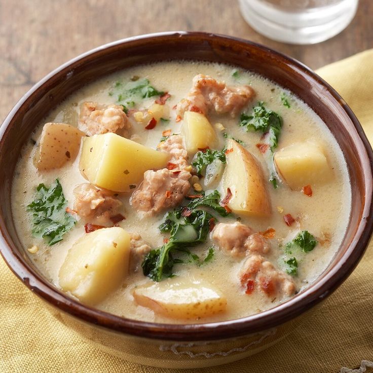 a bowl of soup with meat, potatoes and spinach