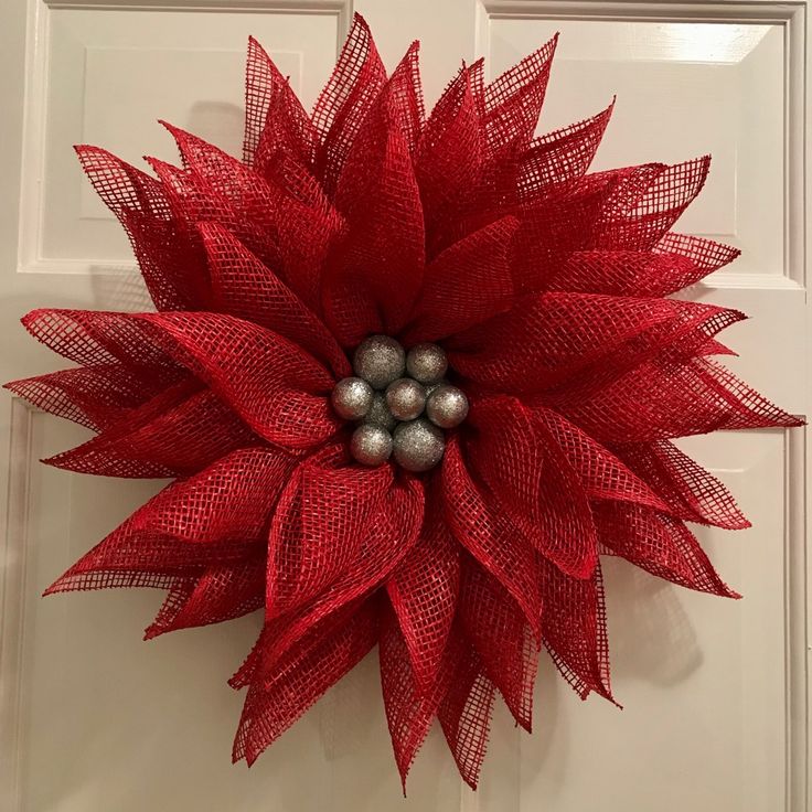 a red wreath with silver balls hanging on the front door