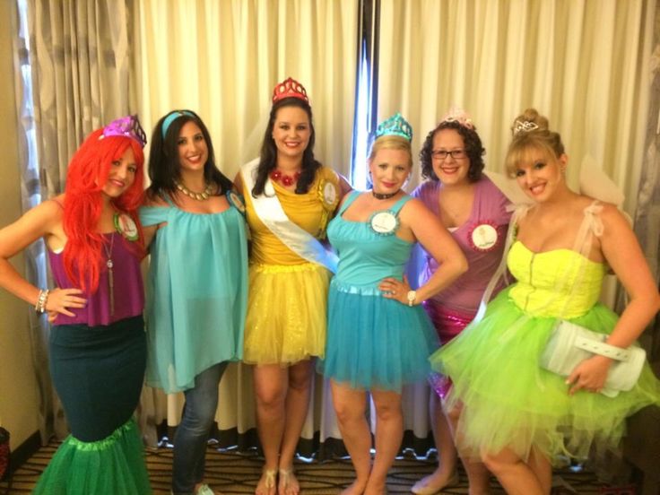 a group of women standing next to each other in dresses and tiaras, posing for the camera