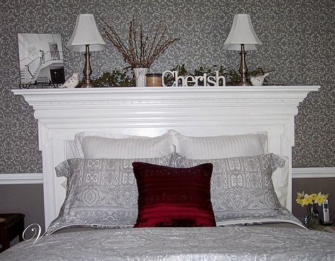 a bed with two lamps on top of it next to a wallpapered wall