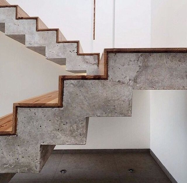 the stairs are made of concrete and wood with white walls in the backround