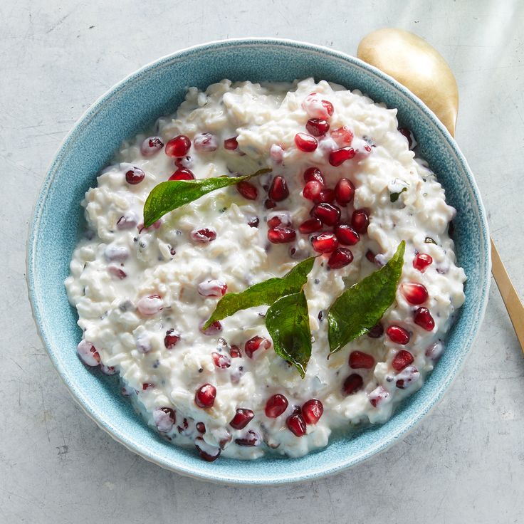 a blue bowl filled with mashed potatoes and pomegranate