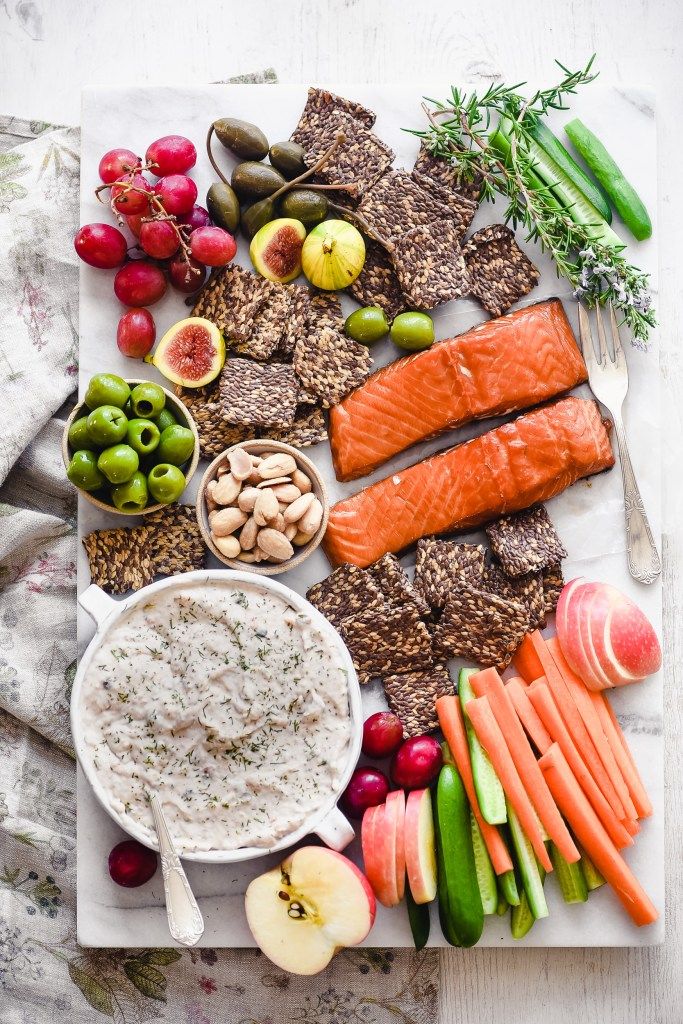 a platter with carrots, apples, celery, crackers and other foods