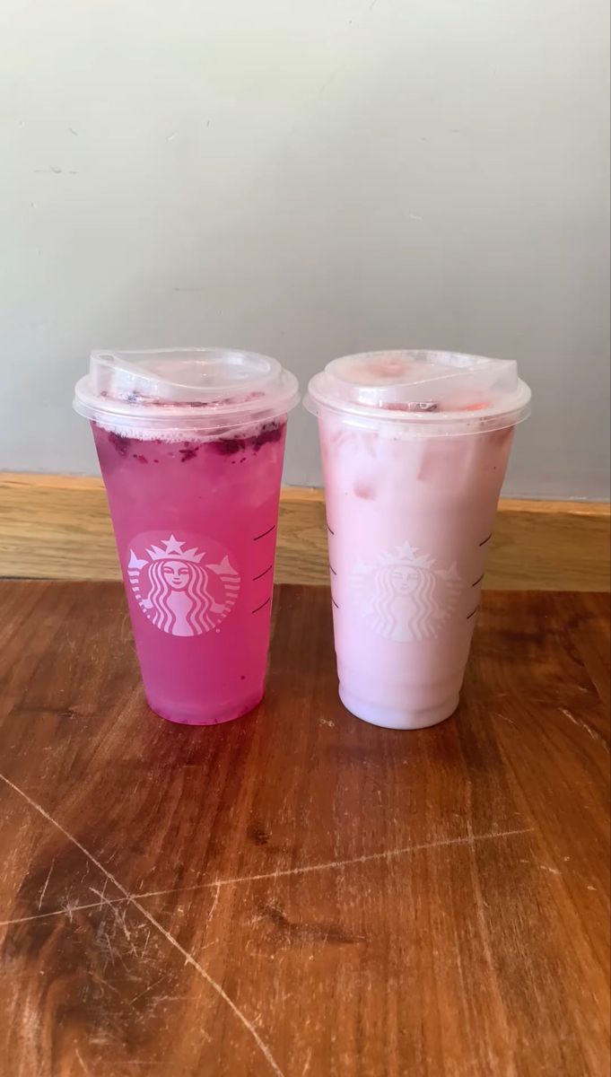 two starbucks drinks sitting on top of a wooden table