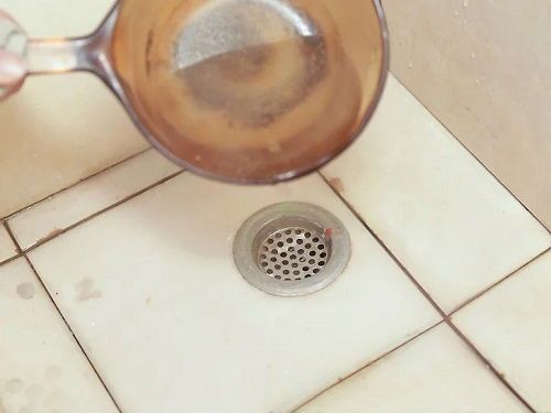 a strainer that is on the floor next to a grate with water in it