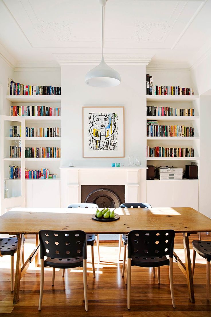 a dining room table and chairs with bookshelves in the backgroung