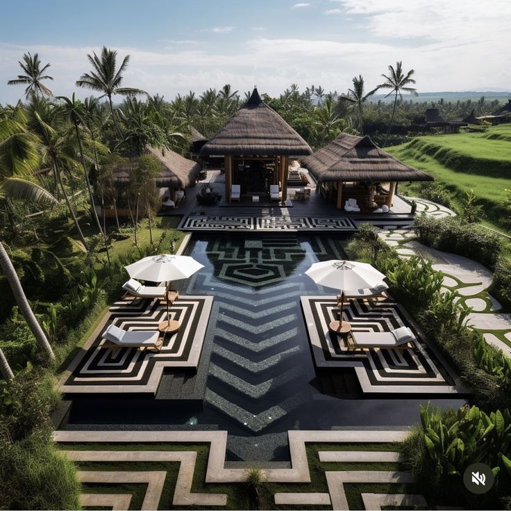 an aerial view of a resort pool with lounge chairs and umbrellas in the foreground