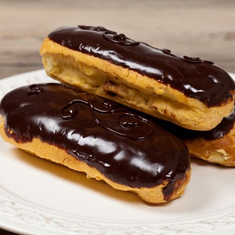 two chocolate covered donuts sitting on top of a white plate