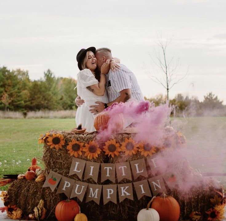 a man and woman kissing on top of a hay bale decorated with sunflowers