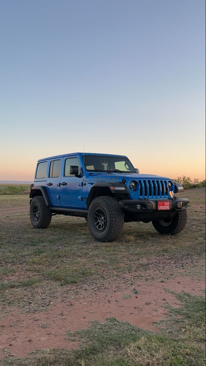 a blue jeep is parked in an open field