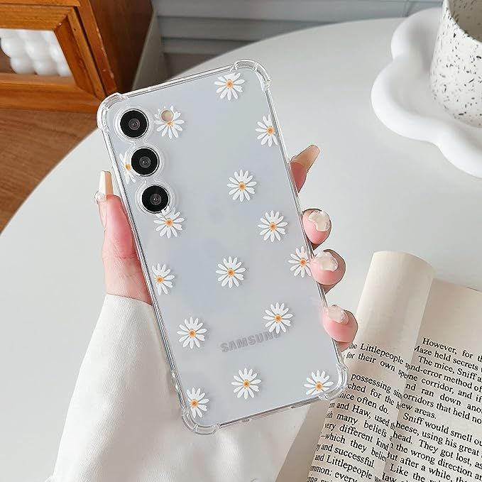 a woman holding up her phone case with daisies on it