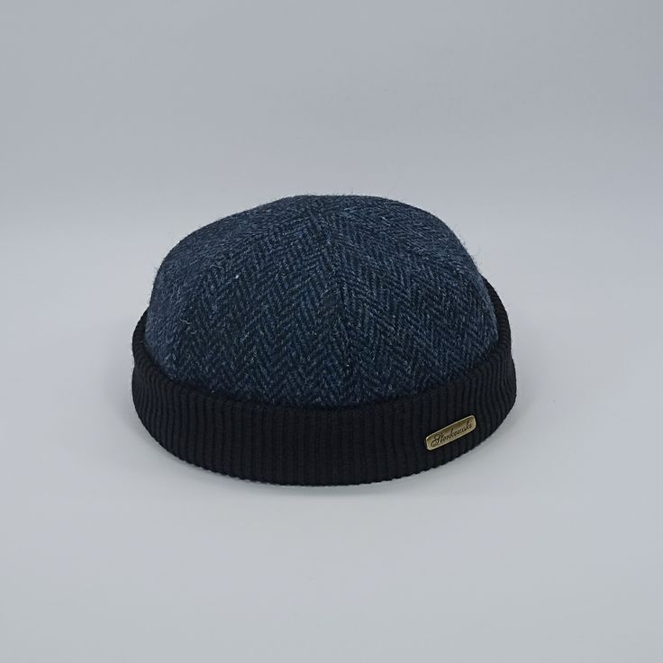 This beanie is a limited edition prototype that has yet to be released for purchase, making it a true gem for aficionados of this design. Don't miss the chance to become the fortunate owner of this one-of-a-kind and exclusive limited edition cap. Introducing the Docker cap, a refined and practical accessory crafted from the finest Harris Tweed fabric, comprised of 100% pure wool. Harris Tweed is renowned for its unparalleled quality among all woolen textiles. This cap has been meticulously desig Outdoor Cap With Herringbone Pattern, Navy Flat Cap For Winter, Navy Wool Casual Hat, Casual Navy Wool Hat, Navy Wool Cap, Outdoor Hats With Herringbone Pattern And Short Brim, Blue Outdoor Beanie Hat, Outdoor Blue Beanie Hat, Outdoor Herringbone Pattern Hat With Short Brim