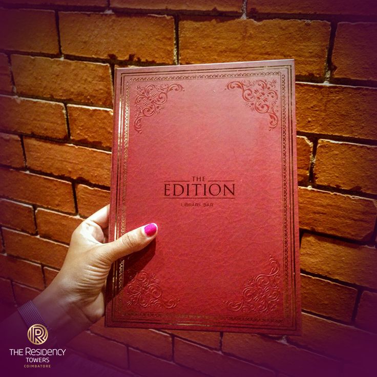 a person holding up a red book in front of a brick wall with the title, the editor