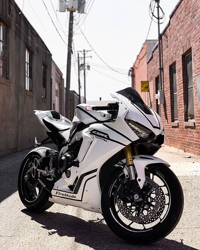 a white motorcycle parked in front of a brick building