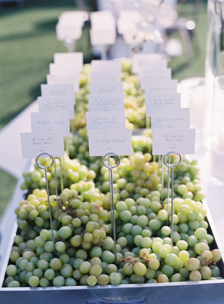 there are many grapes on the table with place cards in them for guests to eat