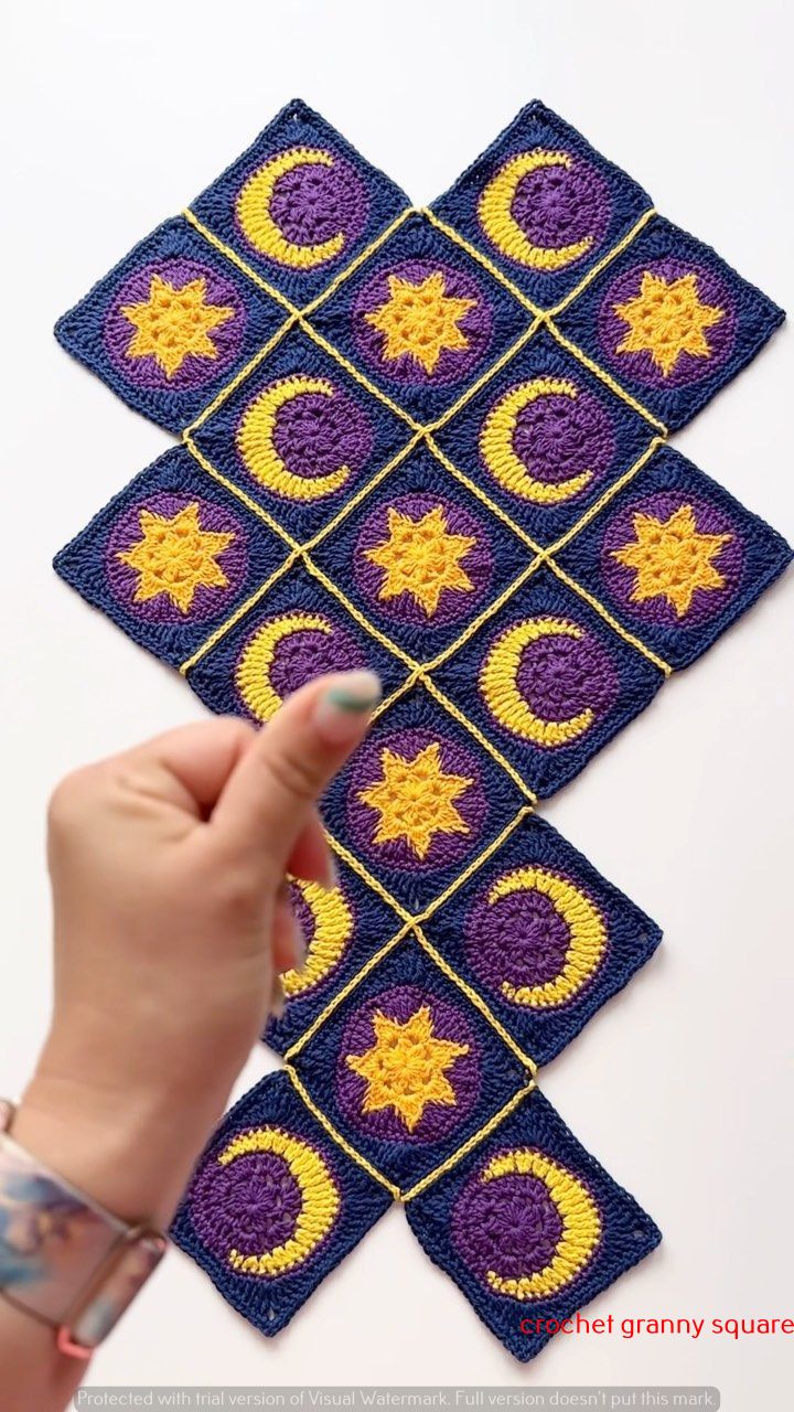 someone is pointing at the crocheted stars and moon squares that are on top of each other