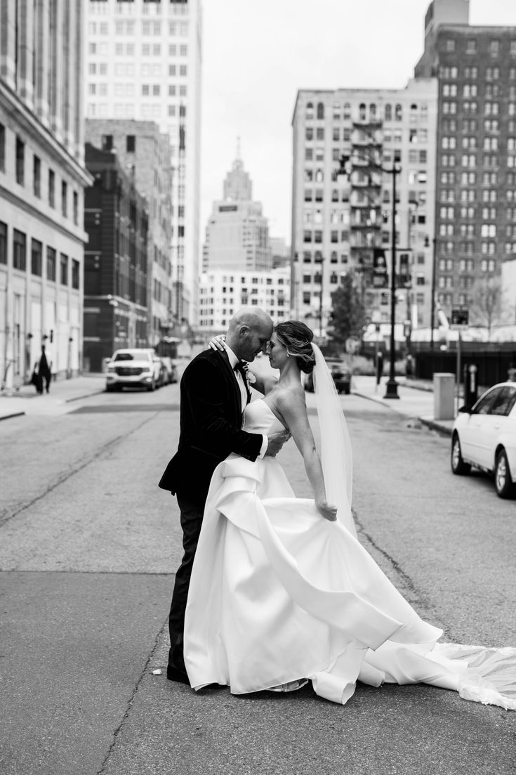 a bride and groom kissing on the street in front of tall buildings with skyscrapers