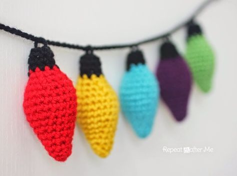 crocheted christmas lights hanging from a string on a white wall with black cord