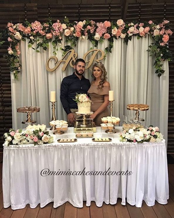 a man and woman standing in front of a table with cupcakes on it