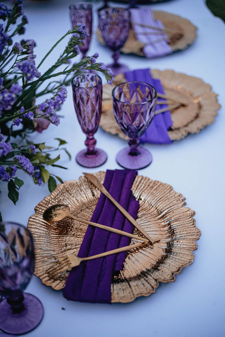 the table is set with purple and gold plates