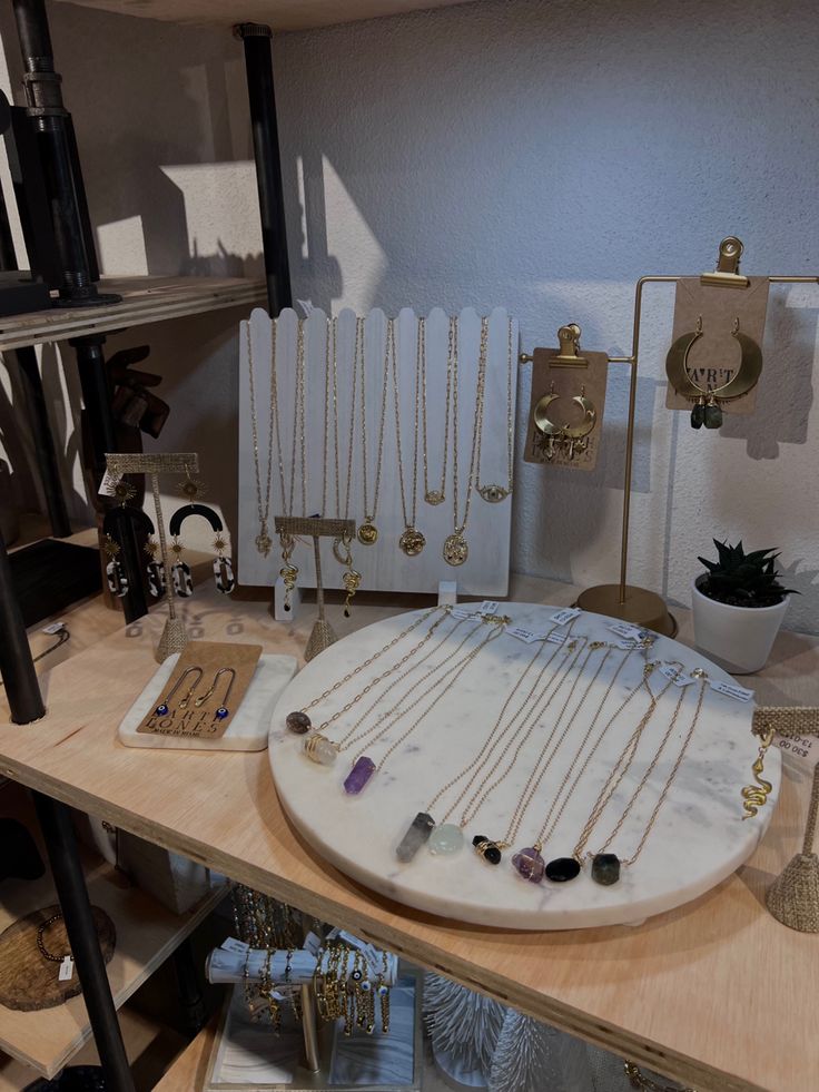 a table topped with lots of necklaces next to a shelf filled with other items