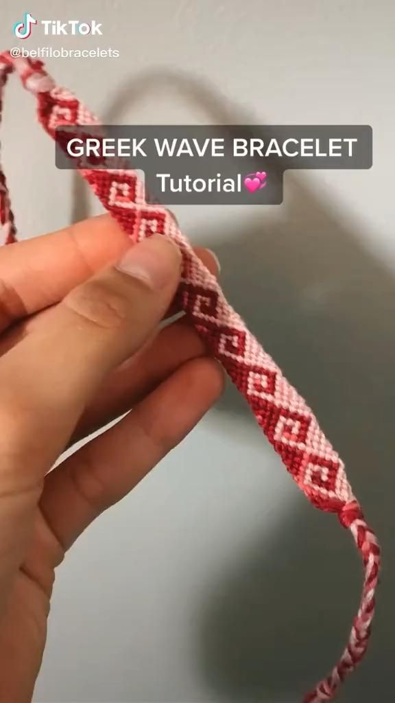 someone is stitching a red and white ribbon with the words greek wave bracelet on it