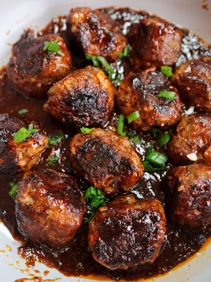 meatballs with sauce and parsley in a white bowl