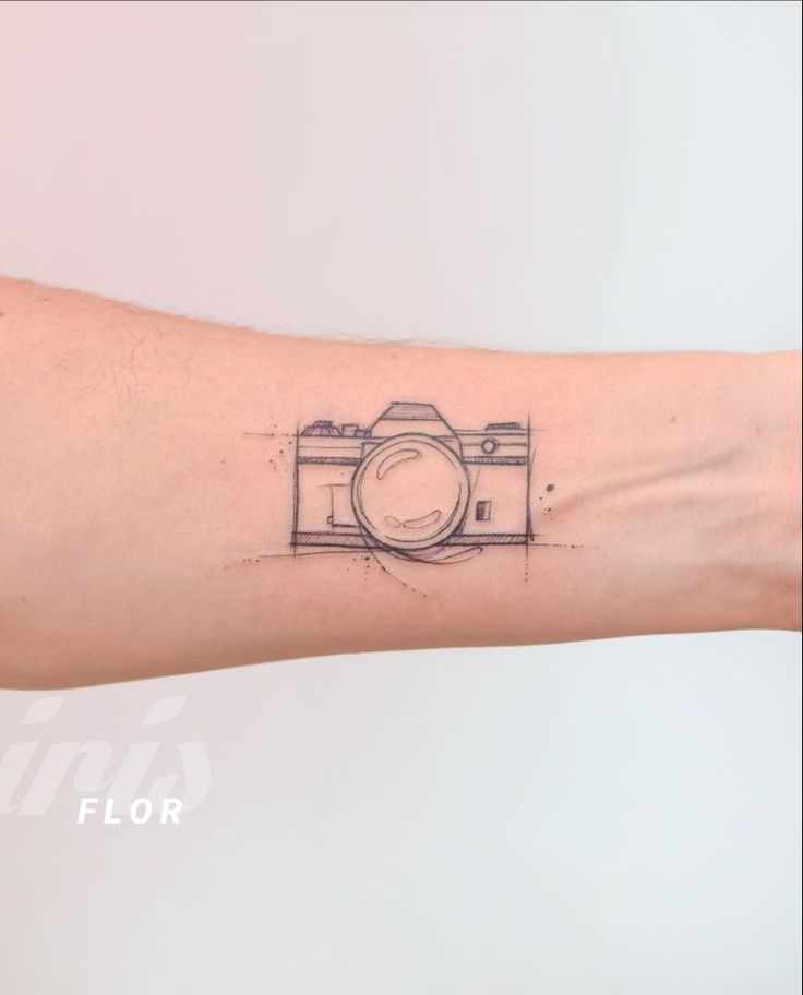 a person's arm with a camera tattoo on it