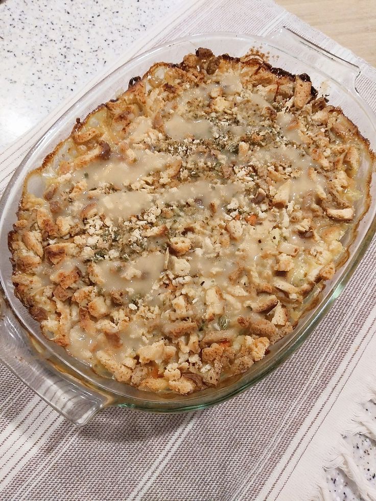 a casserole dish with meat and cheese in it sitting on a tablecloth