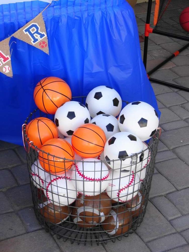 a basket full of basketballs and balls sitting on the ground next to a blue tarp