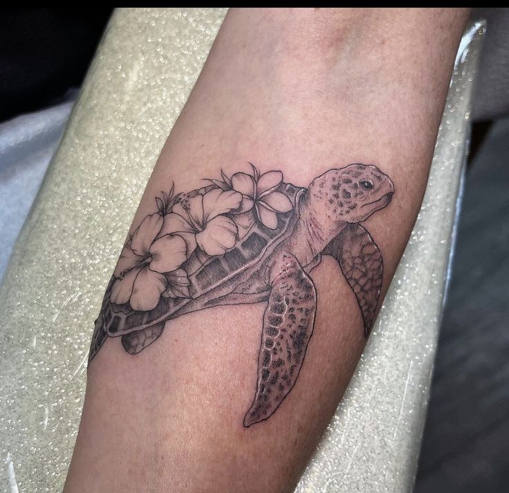 a tattoo with a turtle and flowers on it