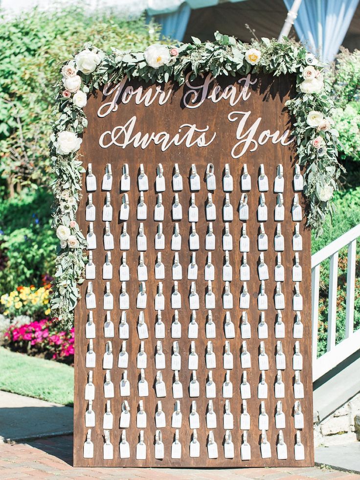 a wooden sign with flowers and greenery on it