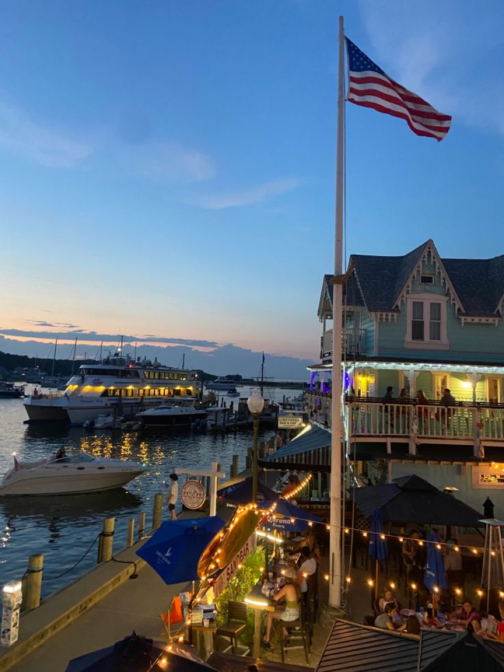 an american flag is flying at the end of a pier with boats in the water