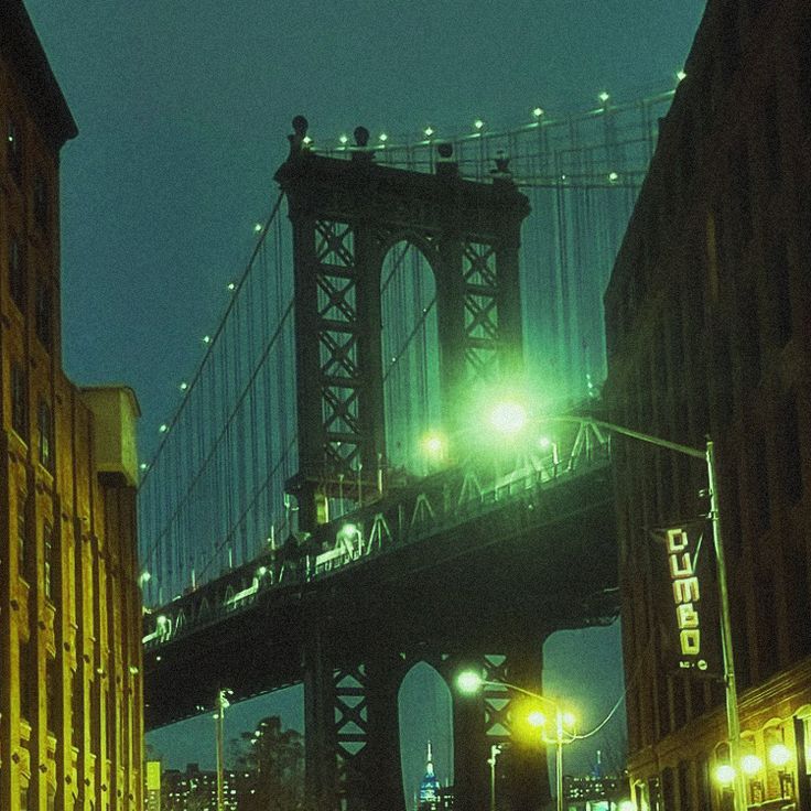 the bridge is lit up at night and it's lights shine brightly on the street