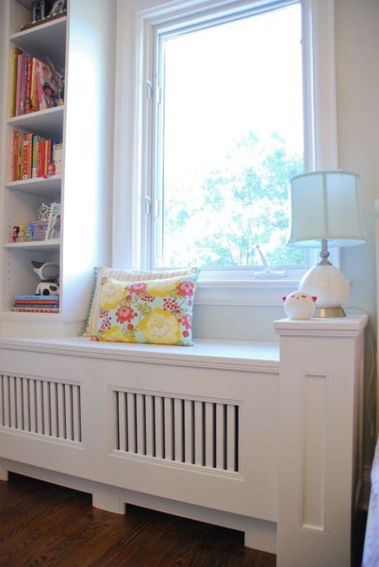 there is a window seat in the corner of this room with bookshelves on either side