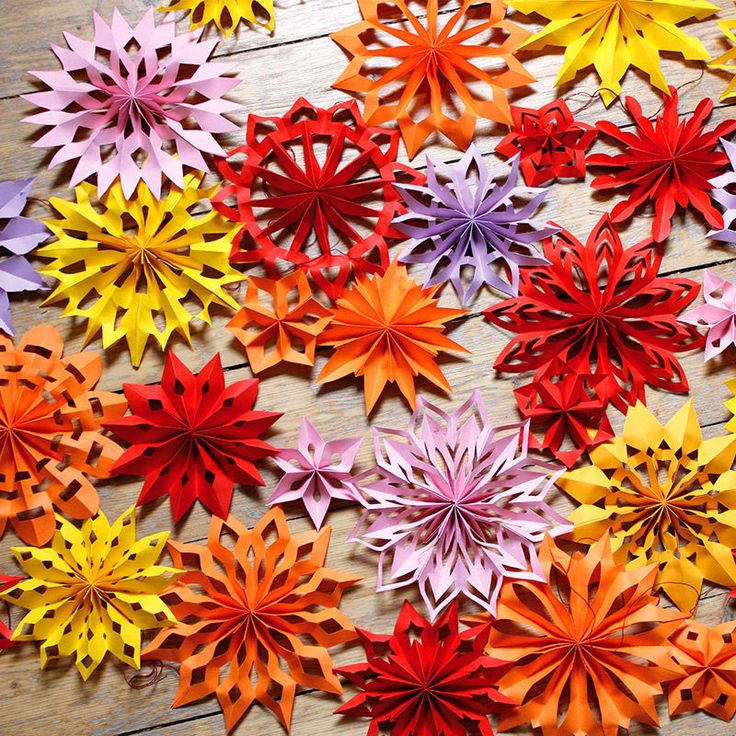 many different colored paper flowers on a wooden surface