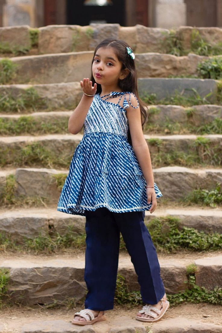 "Perfect for summer weddings and festivals this lehengha and top (set of 2) is an eye turner. Shouting with oodles of comfort during the festivities this cotton peplum suit is going to make your little one feel like herself while enjoying the festive season. Kurta - Blue leheriya with silver top, off shoulder look with tie ups on 1 shoulder. Payjama - Navy blue payjama makes it a comfy wear for your little ones as it comes with elasticated waist with drawstring for easy wear.   Fabric - Cotton C Sleeveless Pant Set For Festive Summer, Sleeveless Cotton Traditional Wear For Festivals, Festive Sleeveless Sets With Bandhani Print, Festive Sleeveless Cotton Traditional Wear, Spring Cotton Palazzo Set With Dupatta, Festive Sleeveless Bandhani Print Set, Sleeveless Cotton Kurta For Eid, Cotton Bandhani Print Sets For Spring, Festive Cotton Set With Dupatta