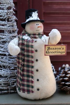 a snowman holding a sign next to some pine cones