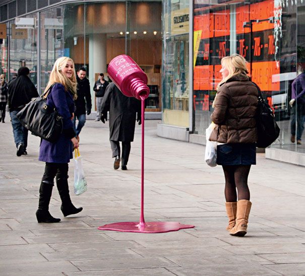 two women are walking down the street with shopping bags and a pink object in front of them