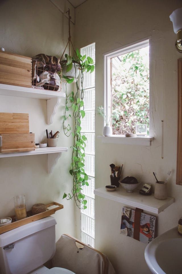 a white toilet sitting in a bathroom next to a window with plants growing on it